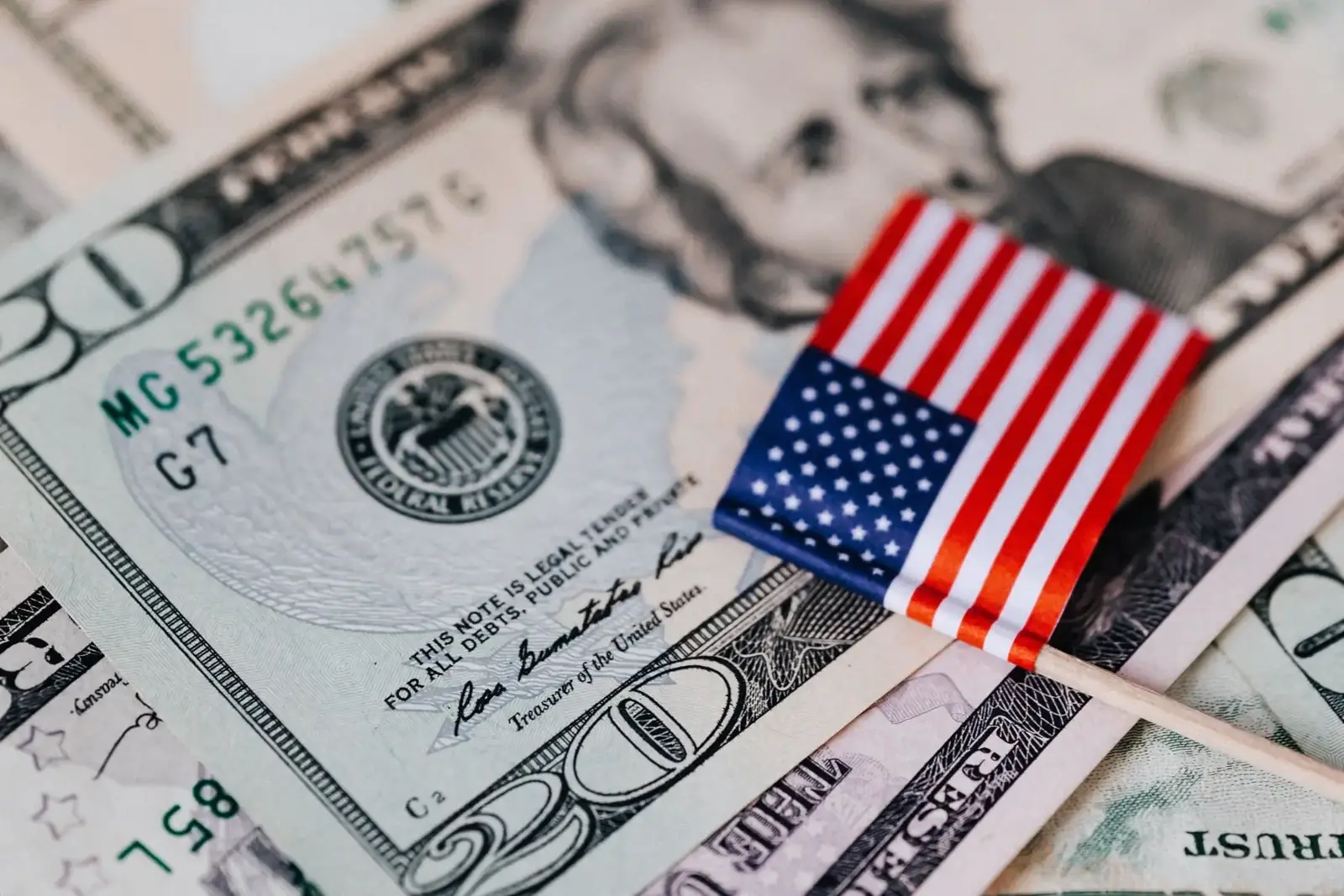 Twenty-dollar bills on a table with a small U.S. flag on top