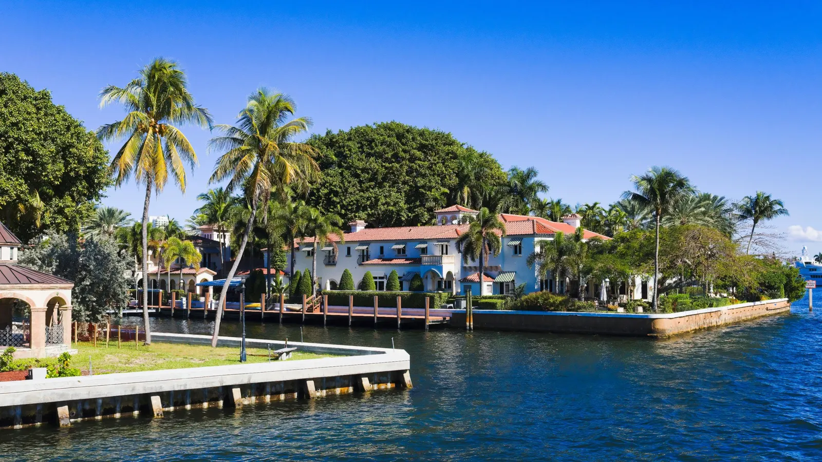 Mediterranean-style houses with red tile roofs and palm trees on a South Florida waterway
