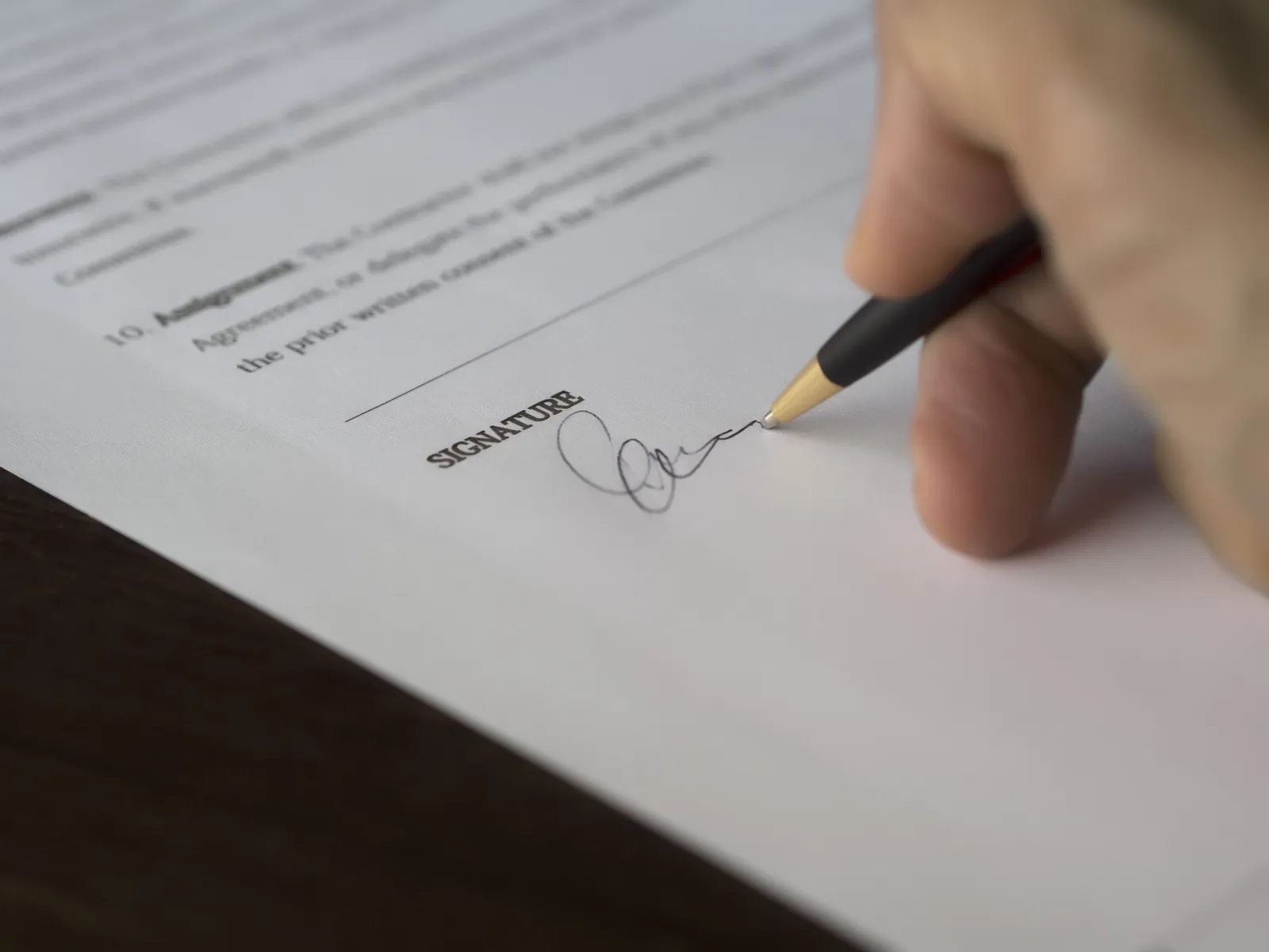 A hand signs a contract with a pen