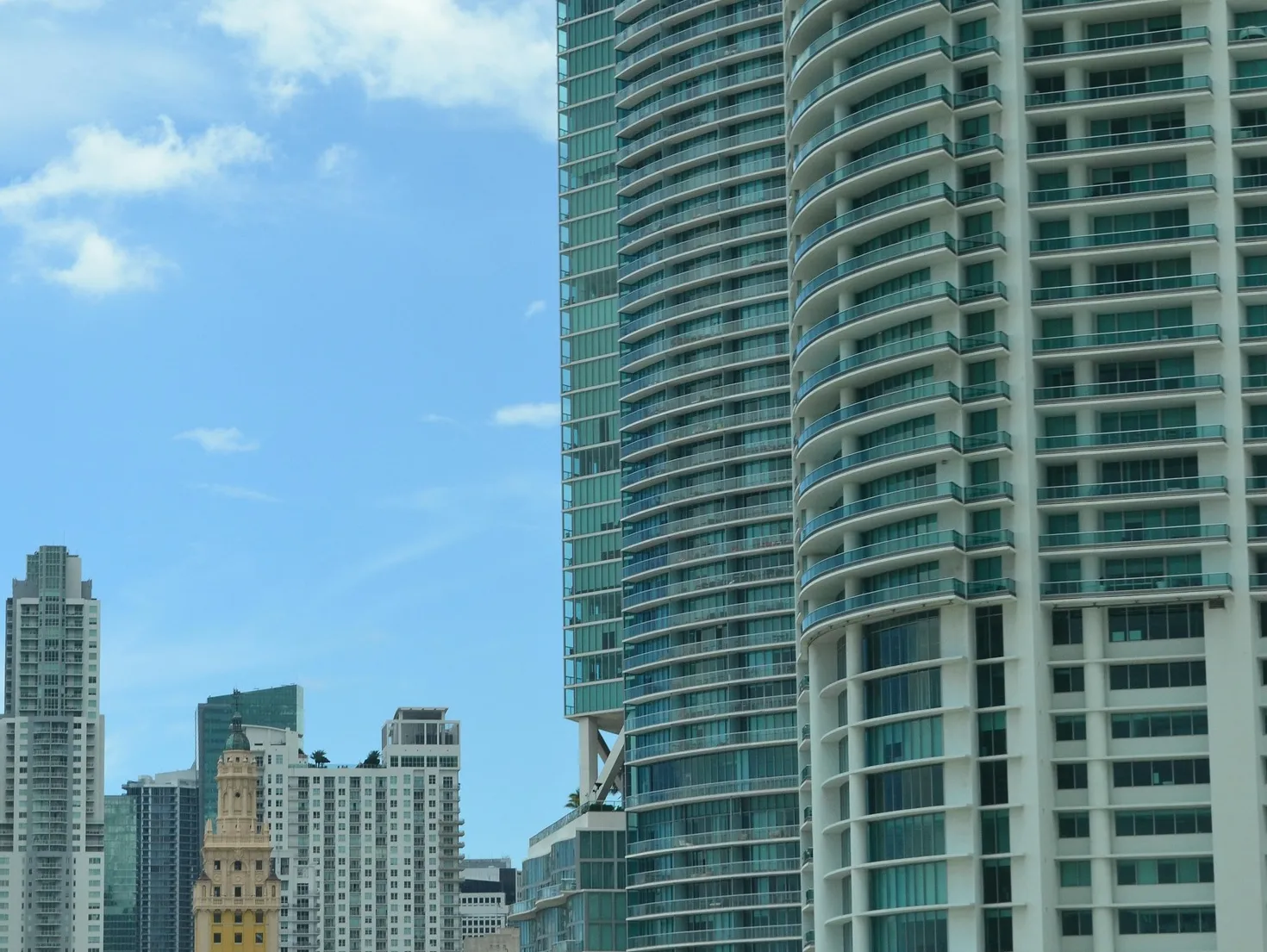 Residential towers in downtown Miami next to the Freedom Tower, under a blue sky