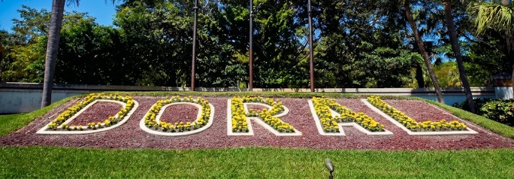 The name Doral spelled out in yellow flowers in a flower bed, surrounded by palm trees