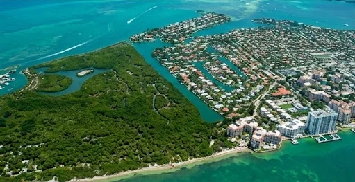 Aerial view of Key Biscayne: the state park's forest and mangroves in the foreground, and the village's homes, canals and towers by turquoise water