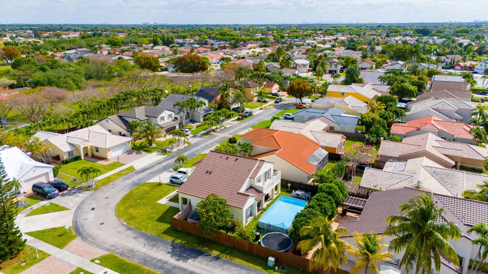Aerial view of a Kendall community with tile-roofed houses, yards, palm trees and a pool