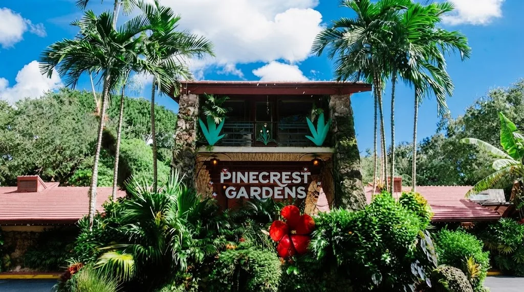 Entrance to Pinecrest Gardens, with red roofs, palm trees and tropical plants