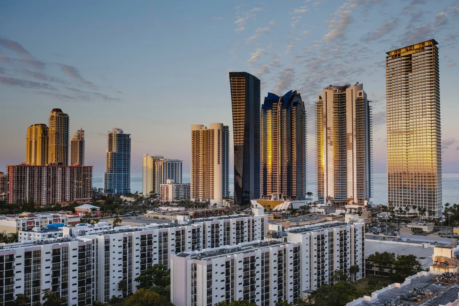 Oceanfront residential high-rises at sunset, with lower apartment buildings in the foreground